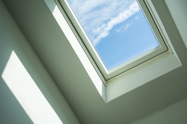 Closed roof window through which you can see the blue sky and white clouds on a sunny day. Modern technologies. Bottom view.